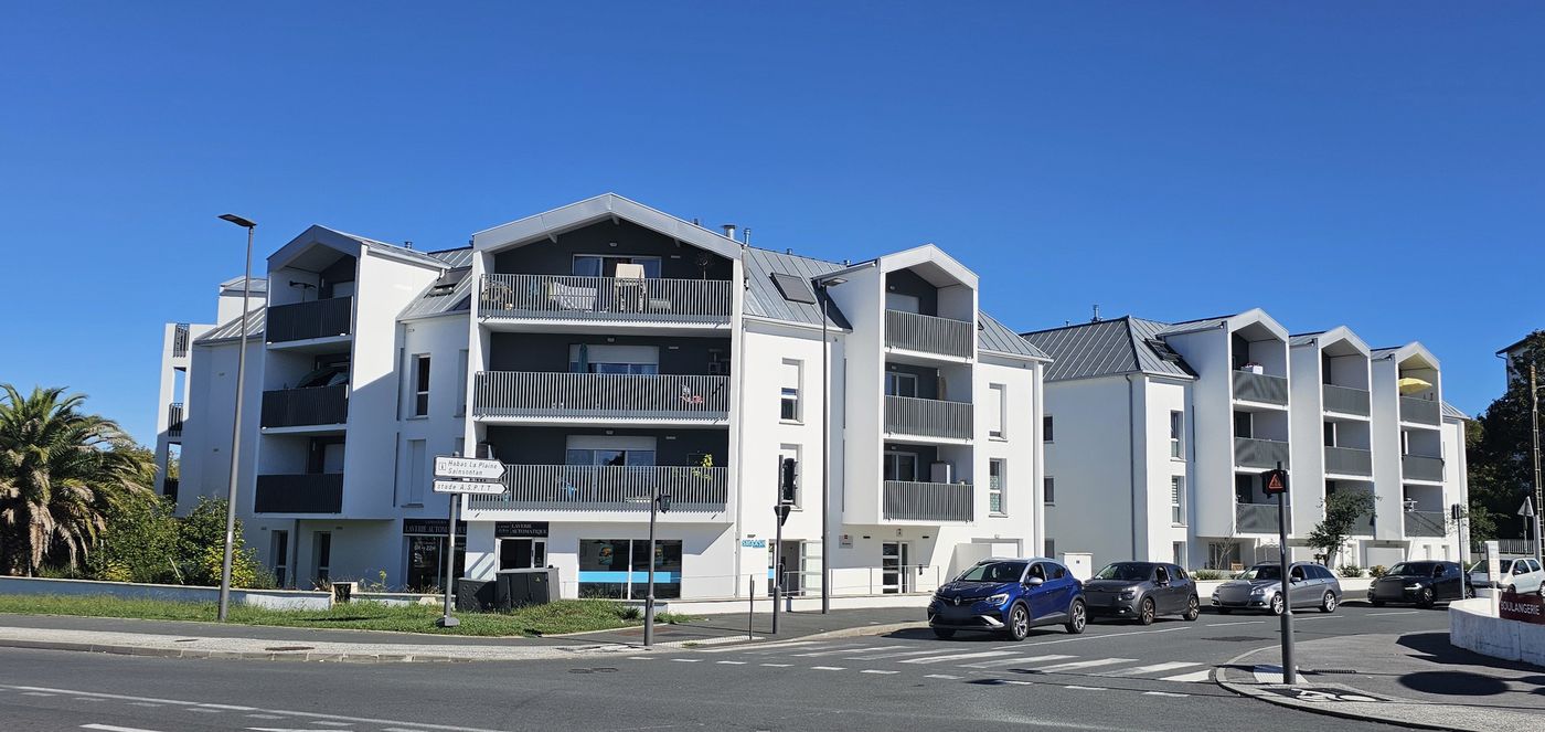 Artzaina à Bayonne : deux bâtiments au rond-point, balcons en émergences verticales et toitures d’aspect zinc.