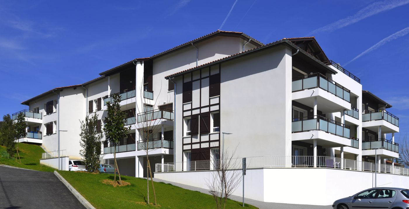 Bilanoa à Saint-Pée-sur-Nivelle : immeuble de logements à balcons vitrés posé sur un talus planté.