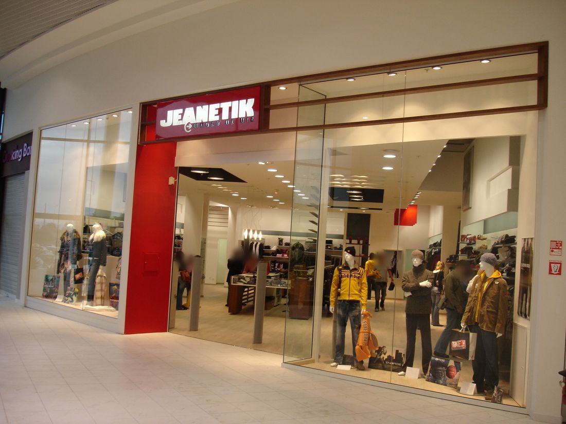 Devanture vitrée d’une boutique en galerie commerciale : cadre bois, vitrines toute hauteur.