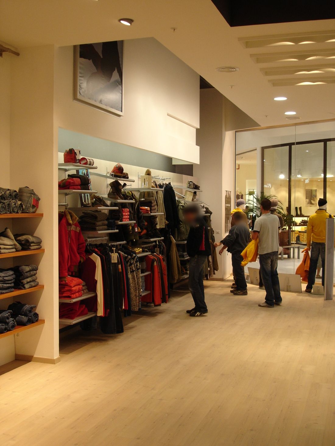 Espace de vente : linéaires muraux sur crémaillère, étagères bois, plafond à lames rétroéclairées.