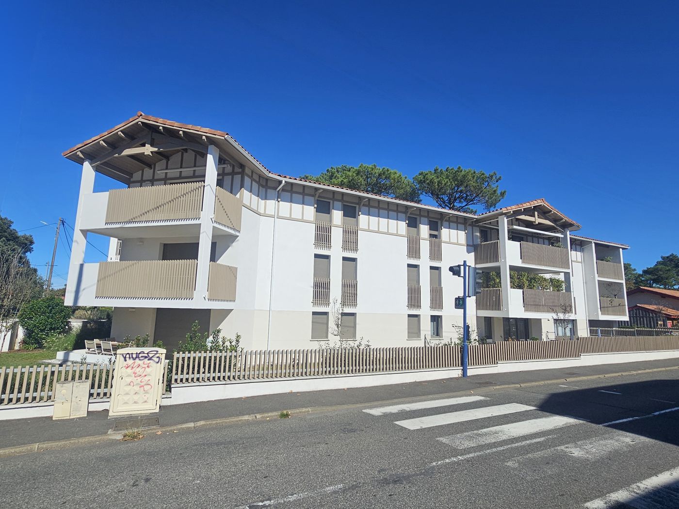 Esprit Océan à Capbreton : angle de rue, pignons à charpente apparente et clôture en ganivelles.