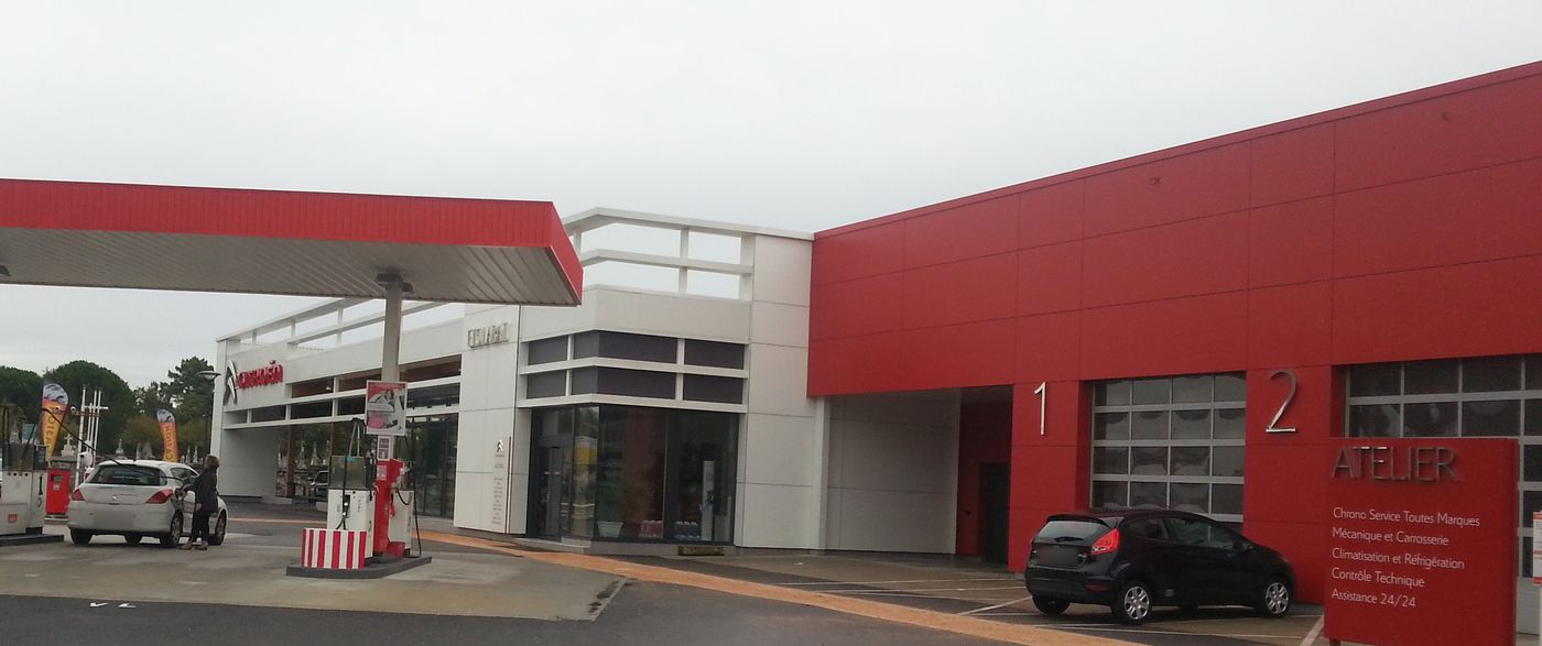 Garage Labat à Lacanau : ateliers rouges et auvent prolongeant la façade.