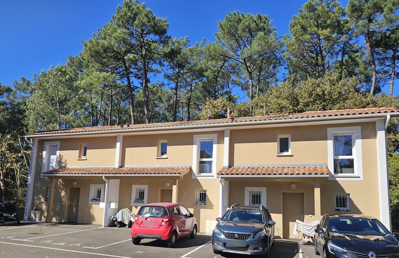 Loustaou à Labenne : façade claire sous toiture en tuiles, pins en arrière-plan.